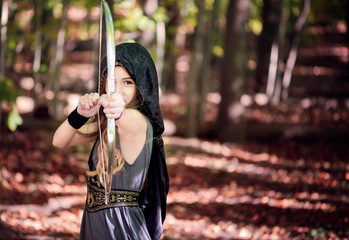 Girl dressed as an archer pointing an arrow