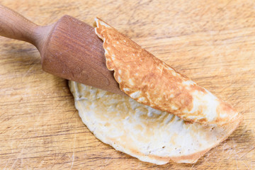 Finished Krumkake cookie on a rolling cone, sitting on a cutting board
