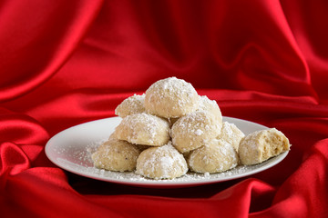 Holiday Russian Tea Cake cookies ready to eat on a white serving plate, one with a bite taken out
