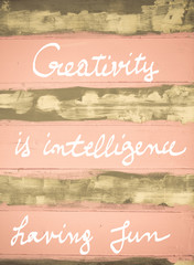 Concept image of Creativity is Intelligence Having Fun motivational quote hand written on vintage painted wooden wall