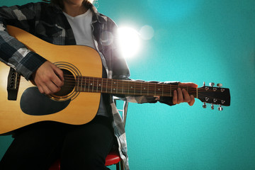 Musician plays guitar on blue background, close up