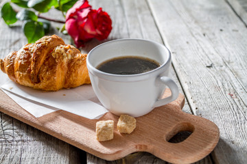 Delicious fresh croissants with coffee and rose