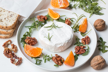 Camembert.Camembert cheese on the plate with fruits and nuts.