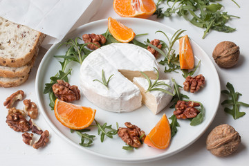 Camembert.Camembert cheese on the plate with fruits and nuts.