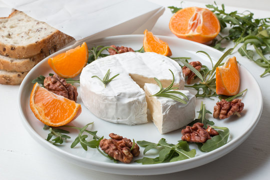 Camembert.Camembert cheese on the plate with fruits and nuts.
