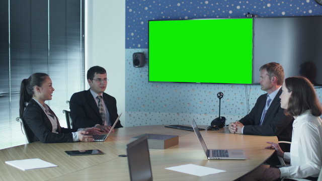 Team Of Office Workers Have Conversation in Conference Room. Display with Green Screen for Mockup on Wall.