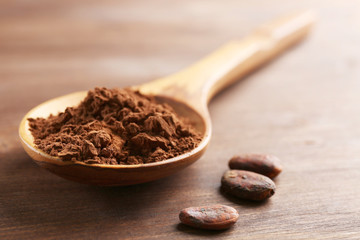Wooden spoon with cocoa powder on the table, close-up