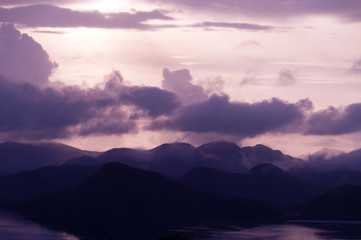 Silhouette of Mountains Above the Water under purple cloudscape clouds at sunset