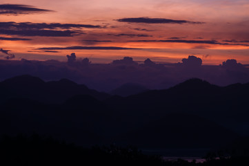 Silhouette of Mountains Above the Water under purple cloudscape clouds at sunset