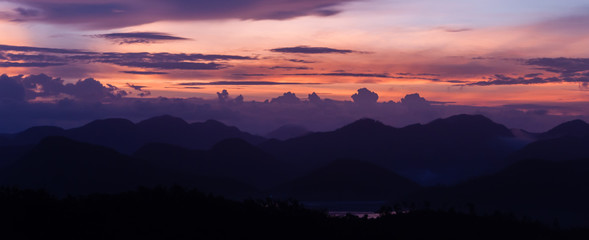 Silhouette of Mountains Above the Water under purple cloudscape clouds at sunset