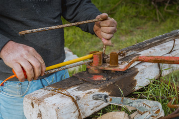 Iraqi blacksmith bending steel bar in old rusty instrument 
