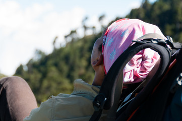 Young Man with pink bandana resting laying on his backpack in the sun sleeping