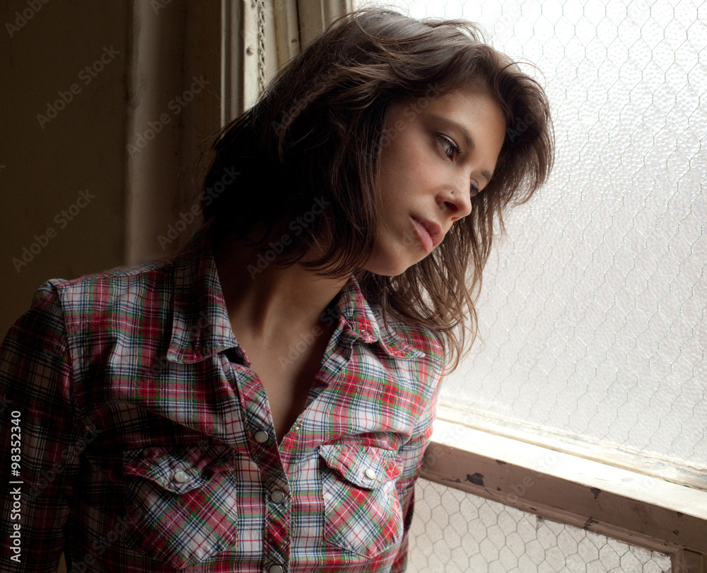 Wall mural wistful young woman looking out window