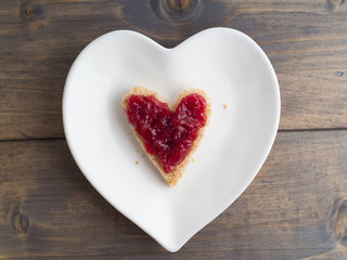 Obraz na płótnie Canvas Toast als Herzform mit Erdbeermarmelade auf einem herzförmigen