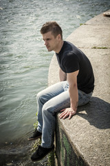 Contemplative teenage boy sitting beside river