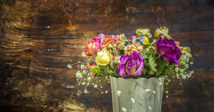 vintage colorful preserved roses on dark tone wooden background
