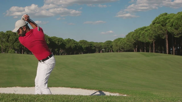 young healthy golfer hitting golf shot with club on course