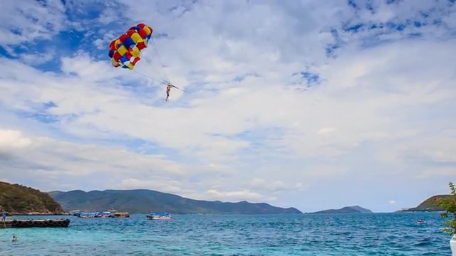 parasailer starts fly from beach over sea against sky on island