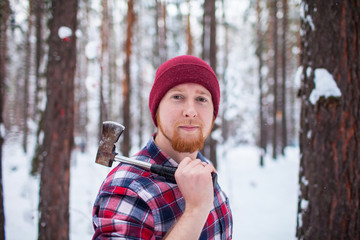 bearded man with an hatchet in the winter forest