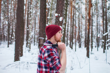 bearded man with an hatchet in the winter forest