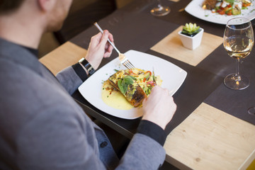 Man eating grilled salmon at restaurant