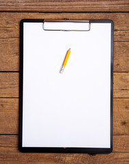 blank paper in clipboard on wooden table