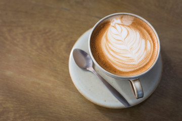 Hot art Latte Coffee in a cup and laptop on wooden table