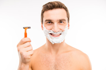 Handsome happy man with shaving foam on his face holding razor