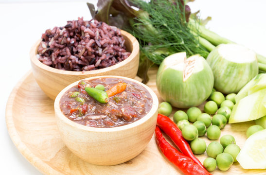 chili paste in wooden cup with vegetable and berry rice on white