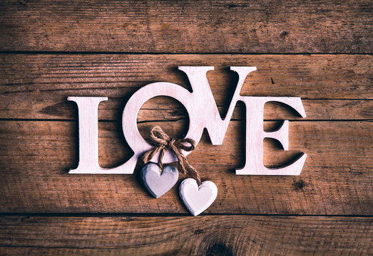 Wooden letters forming word LOVE written on wooden background. St. Valentine's Day. two hearts