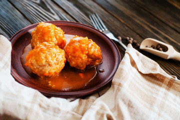 
lunch or dinner , meatballs with rice , carrots, onions , spices and tomato sauce on a wooden background