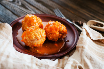 
lunch or dinner , meatballs with rice , carrots, onions , spices and tomato sauce on a wooden background