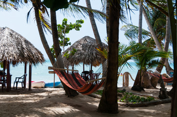 Two Huts With Tables Chairs and Hammock at the white sand beach in front of caribbean sea