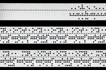 Closeup of perforated punched tape on black background