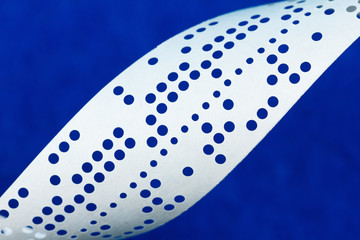 Closeup of perforated punched tape on blue background