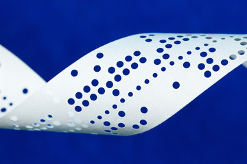 Closeup of perforated punched tape on blue background