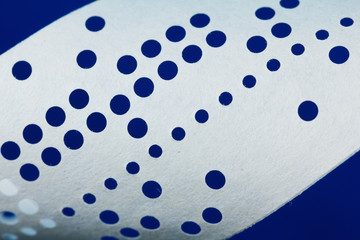 Closeup of perforated punched tape on blue background