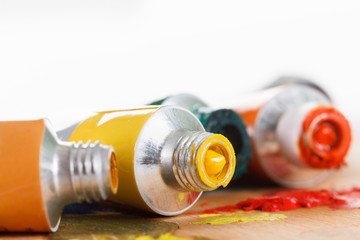 Oil paint tubes and pain brush over colorful artist's palette