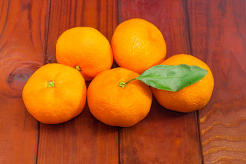 Several mandarin oranges on a dark wooden surface