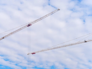 Tower cranes arms on cloudy sky background
