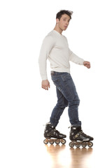 young handsome man with roller skates posing in the studio