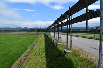 Obraz premium 防雪柵／雪国の山形県で、防雪柵が設置された風景を撮影した写真です。夏場は防雪柵を畳んであり、見通しを妨げないようになってます。吹雪対策の為、本格的な降雪時期になると機能するように設置されます。冬場の猛吹雪の時は防雪柵がなければ、道路が瞬時に吹き溜まりで通行不能になるので非常に重要なものです。