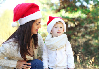 Christmas and family concept - happy mother and child in santa r