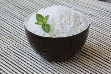 Bowl of steamed rice with mint leaf.