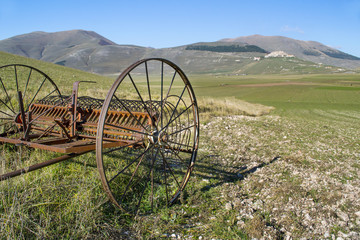 vecchia trebbiatrice in un campo ai piedi dei monti Sibillini in Italia