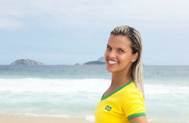 Blonde Frau im Brasilien-Trikot am Meer