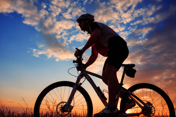 Obraz premium mountain biker silhouette in sunrise