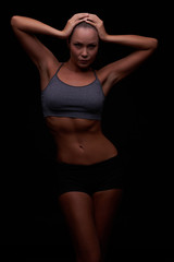 Fototapeta na wymiar Beautiful young girl on a dark background is engaged in fitness