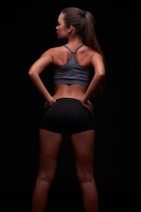 Obraz premium Beautiful young girl on a dark background is engaged in fitness