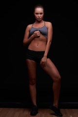 Beautiful young girl on a dark background is engaged in fitness
